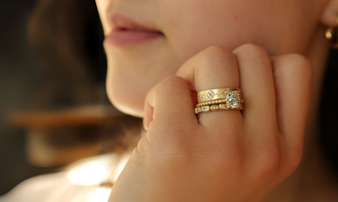 Unique engagement ring and wedding band stack on left hand, photographed in natural light