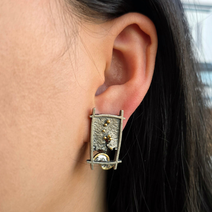 Woman wearing Shoji Lantern diamond stud earrings in oxidized silver and gold from Alara Jewelry