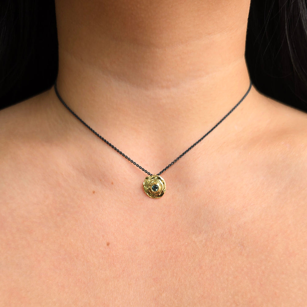 Woman wearing True Aim gold bullet pendant with Montana sapphire from Alara Jewelry