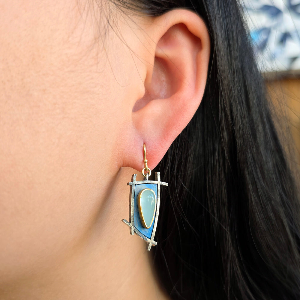 Woman wearing asymmetric aquamarine drop earrings with titanium and gold detailing from Alara Jewelry
