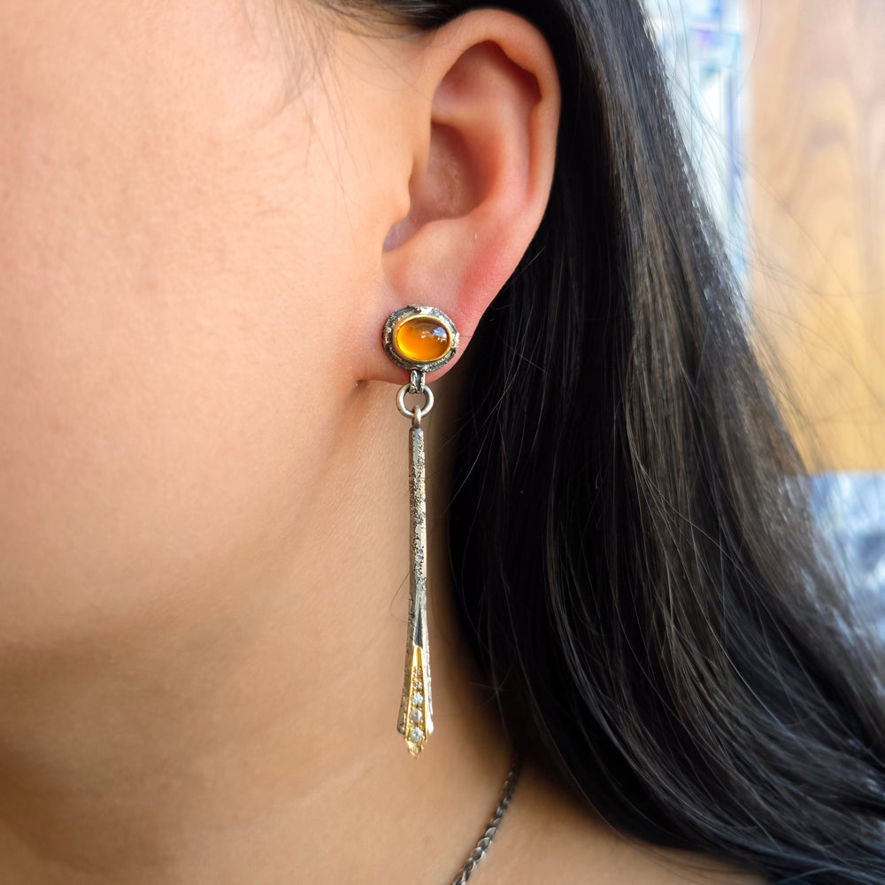 Woman wearing spessartite garnet drop earrings with silver and gold detailing from Alara Jewelry