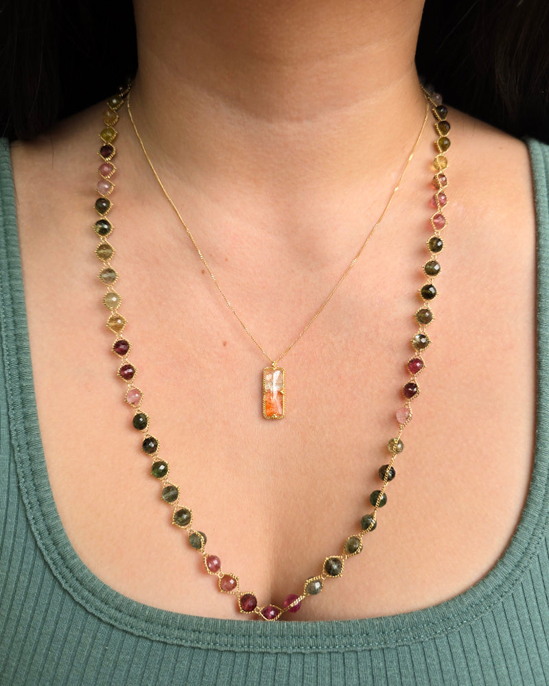 Woman wearing Amáli rainbow tourmaline necklace from Alara Jewelry