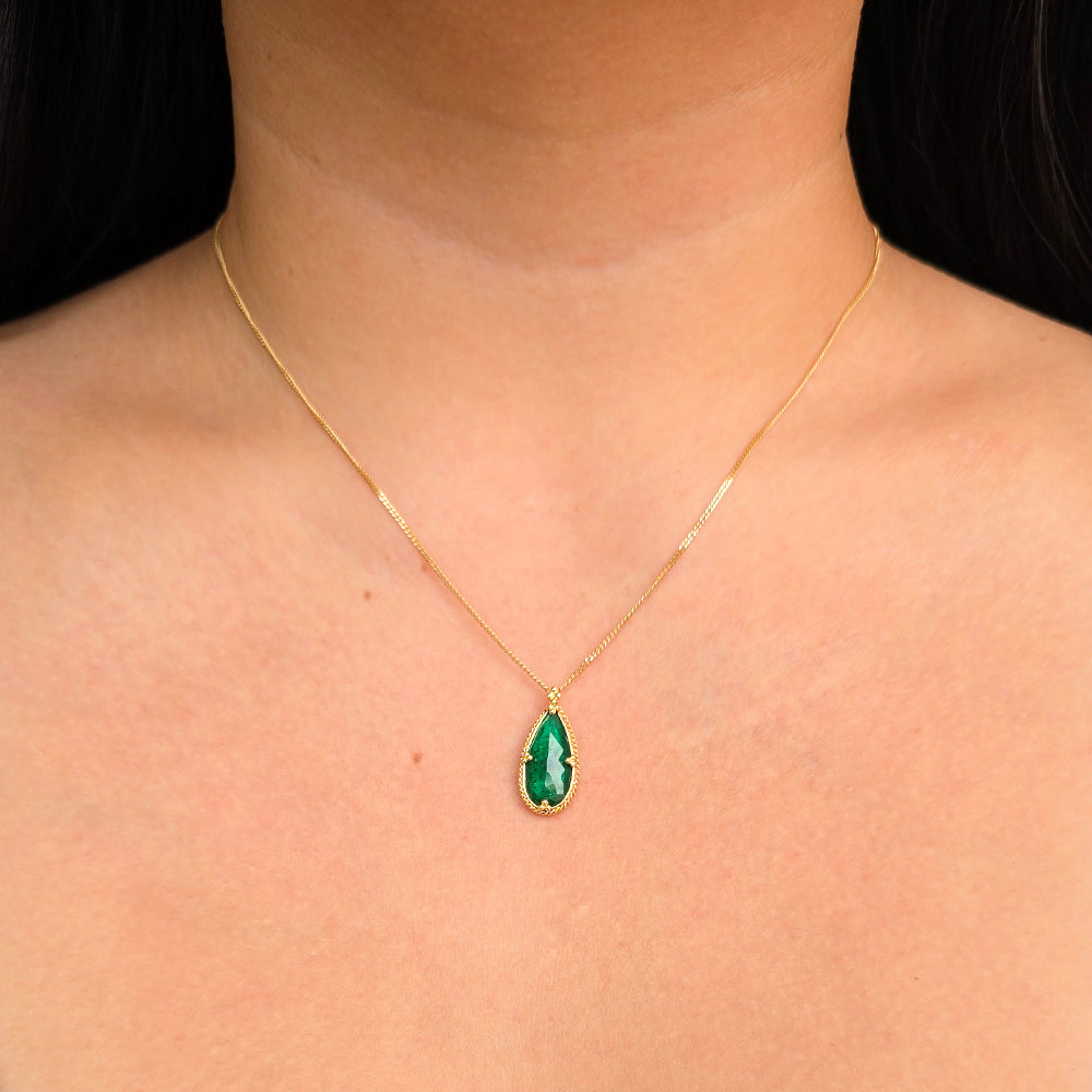 Woman wearing Greenwake pear-shaped emerald necklace by Amáli in 18K yellow gold