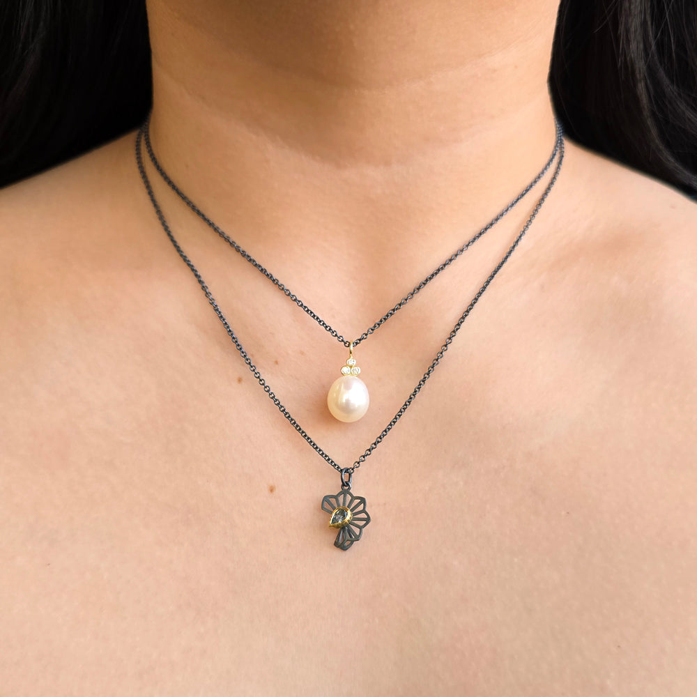 Woman wearing pearl and diamond drop necklace from Alara Jewelry