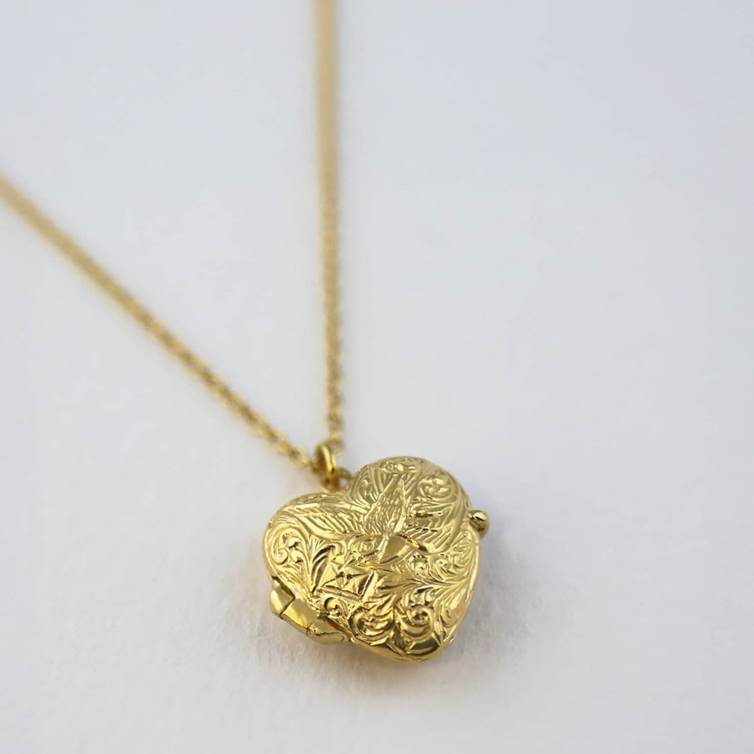 Close-up of hand-detailed bird and envelope motif on locket front