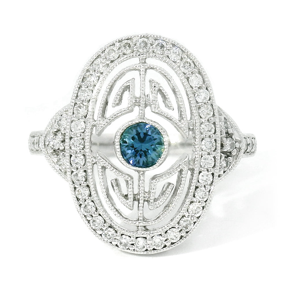 An elegant Art Deco style white gold ring featuring a bright blue Yogo sapphire center stone surrounded by a maze of diamonds and encircled in an outer halo of round brilliant-cut diamonds.