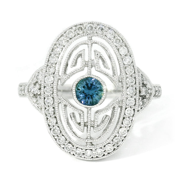 An elegant Art Deco style white gold ring featuring a bright blue Yogo sapphire center stone surrounded by a maze of diamonds and encircled in an outer halo of round brilliant-cut diamonds.