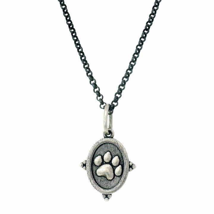 Silver pendant with paw print on a chain against a white background