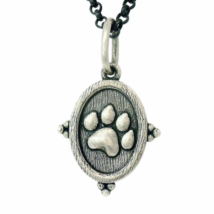 Silver pendant with a paw print design on a white background