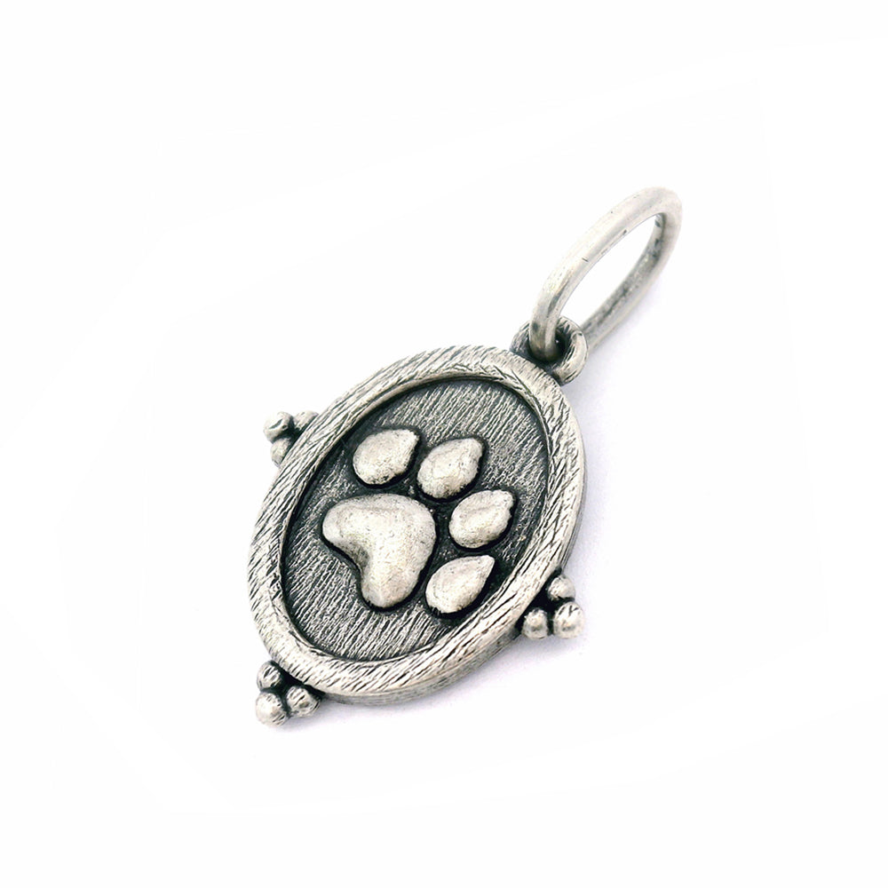 Silver pendant with a paw print design on a white background