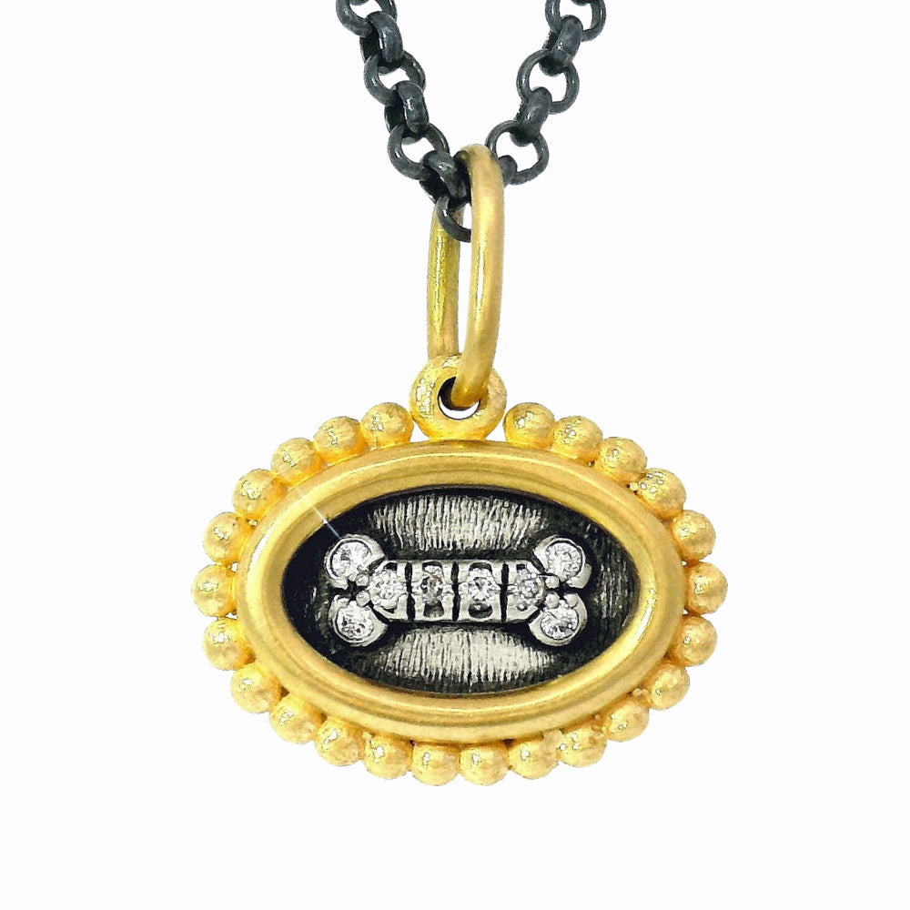 Close-up of oxidized silver and gold reversible charm with diamond accents