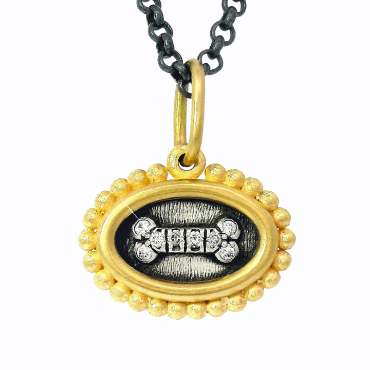 Close-up of oxidized silver and gold reversible charm with diamond accents