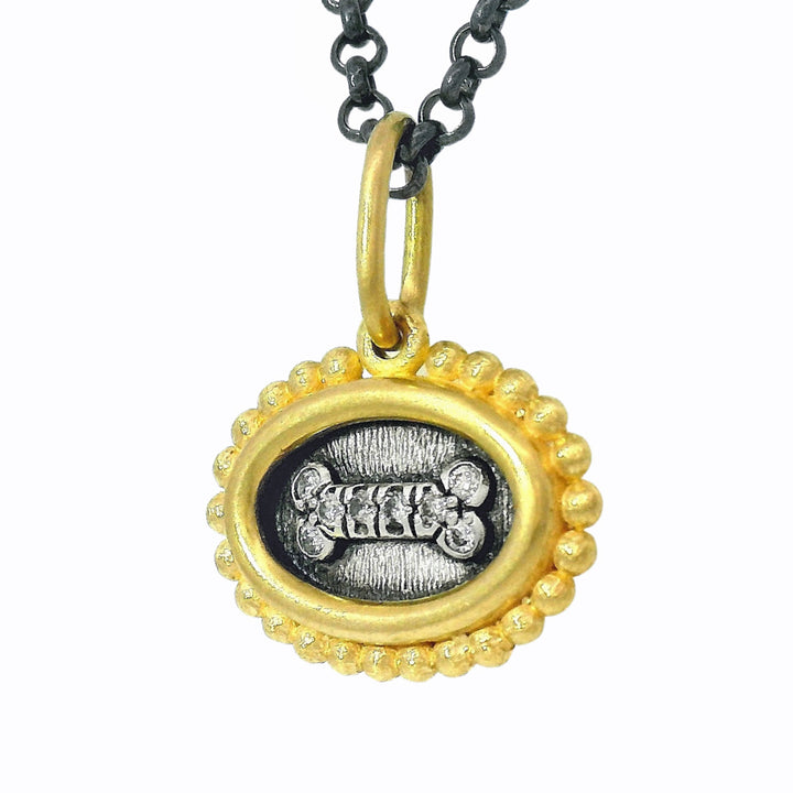 Close-up of oxidized silver and gold reversible charm with diamond accents