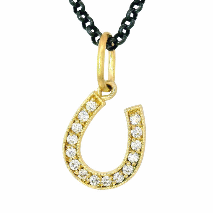 Close-up of diamond-set horseshoe charm with satin gold finish