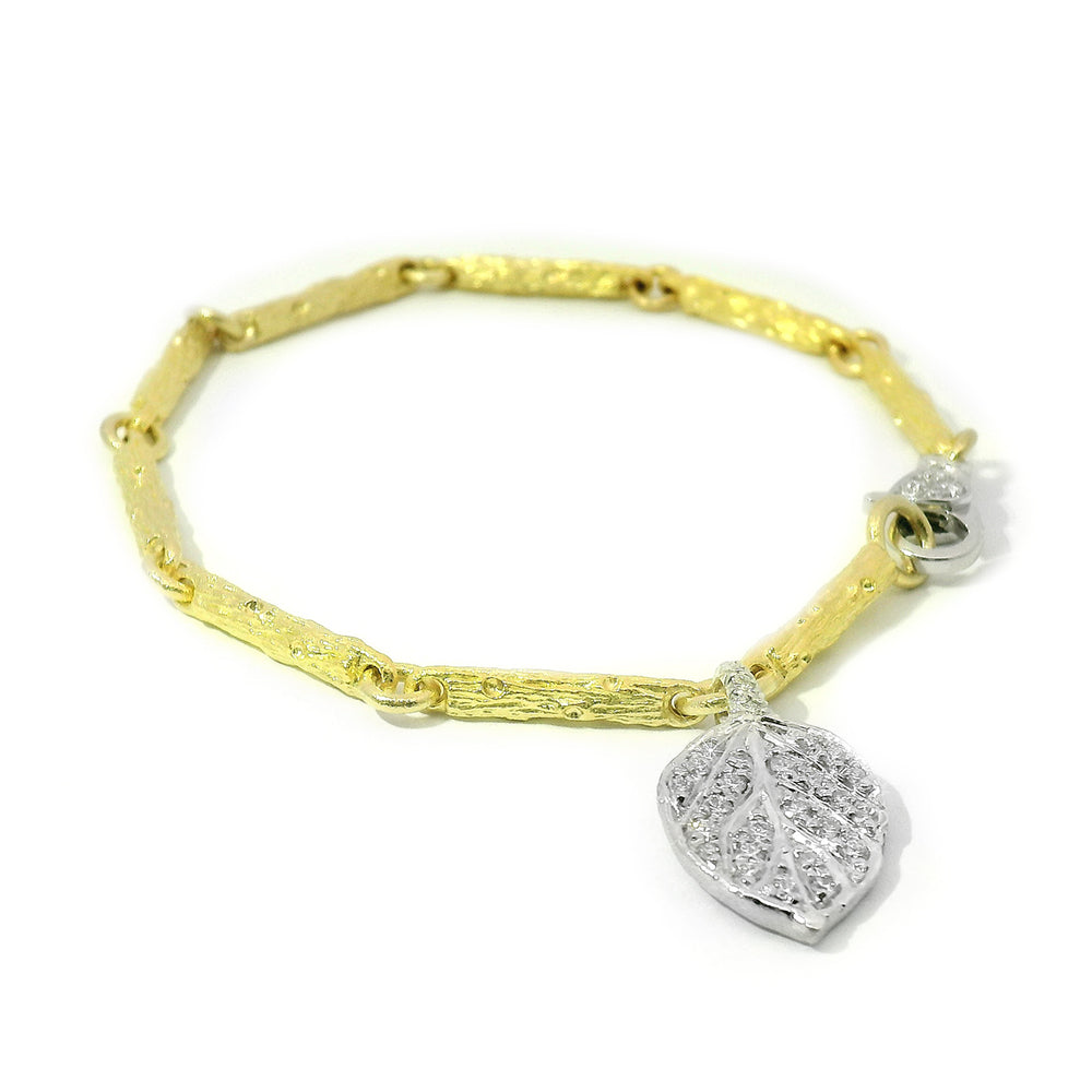 Textured gold bracelet with pavé diamond leaf charm in white gold