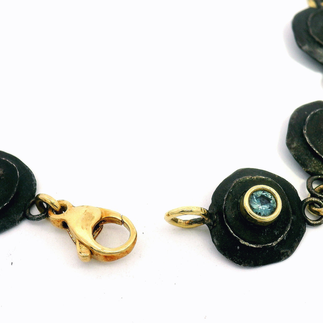 Close-up of round brilliant-cut Montana sapphire set in bullet-inspired link with clasp