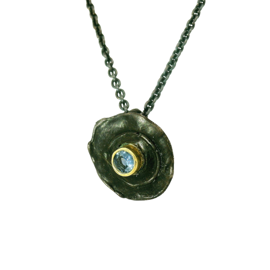 Close-up of blue Montana sapphire set in darkened silver pendant
