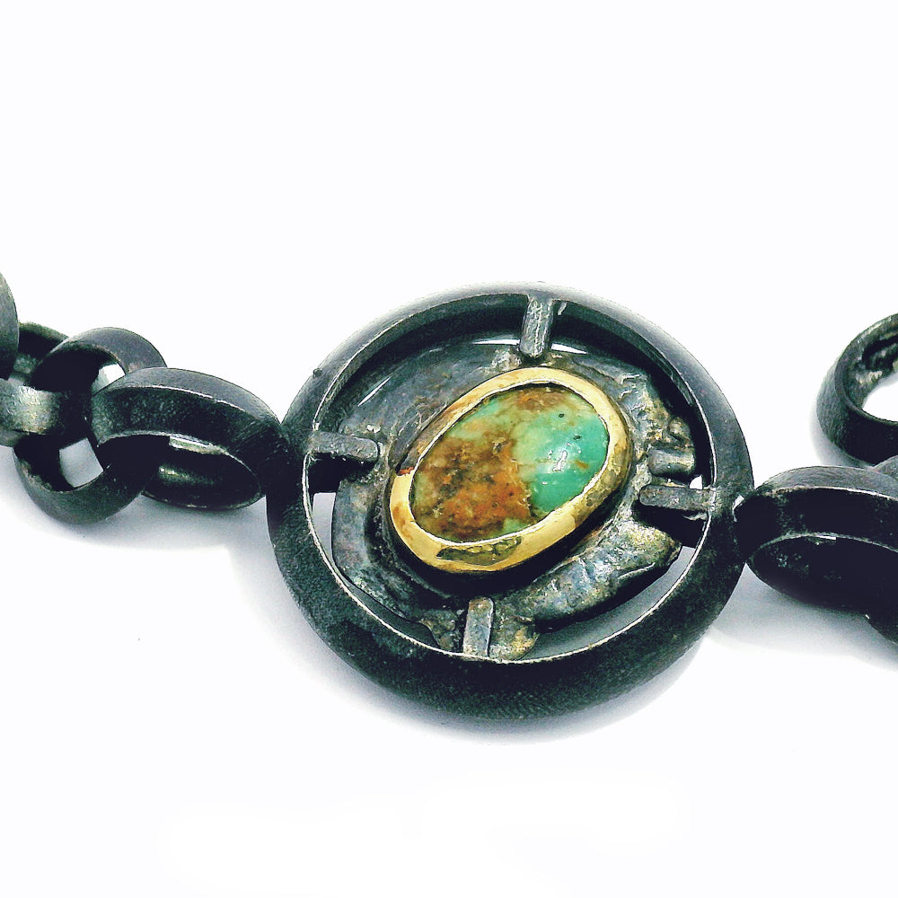 Close-up of natural turquoise cabochon in gold bezel on silver bracelet