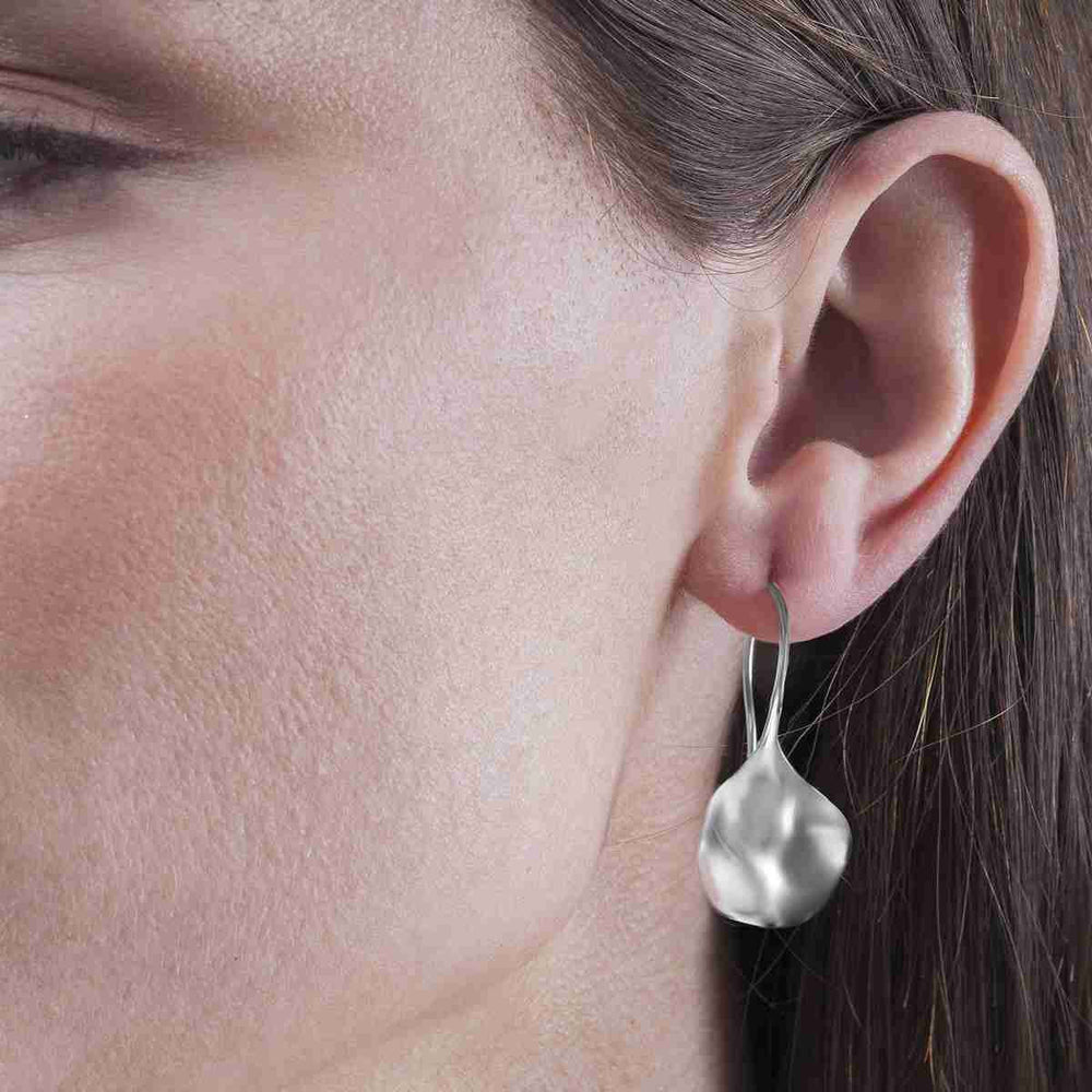 Woman wearing sculptural sterling silver drop earrings by Jorge Revilla from Alara Jewelry