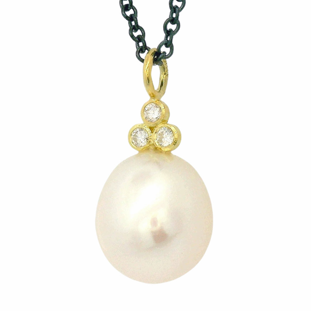 Close-up of pearl drop necklace with three round brilliant-cut diamonds