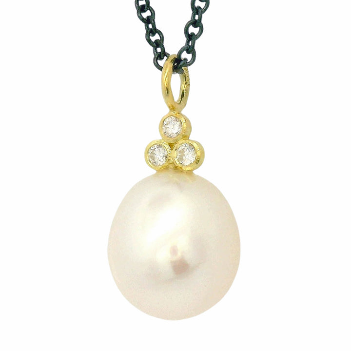 Close-up of pearl drop necklace with three round brilliant-cut diamonds