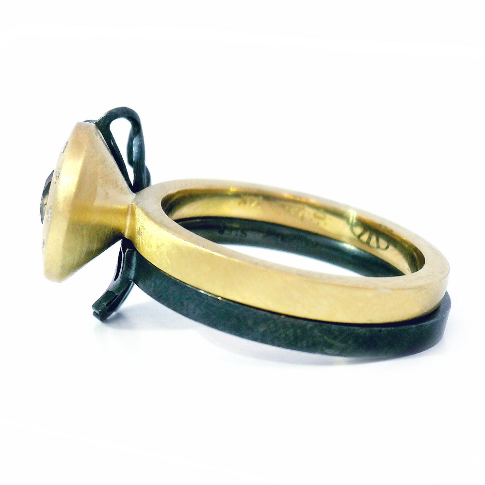 Close-up of oxidized silver origami fold ring nested beside gold sapphire ring
