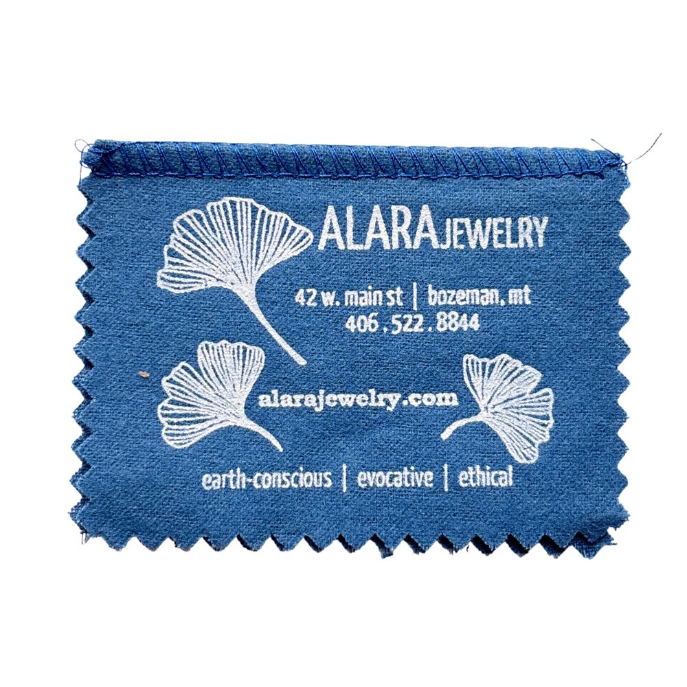 Blue jewelry cleaning cloth with ALARA Jewelry branding and contact information.
