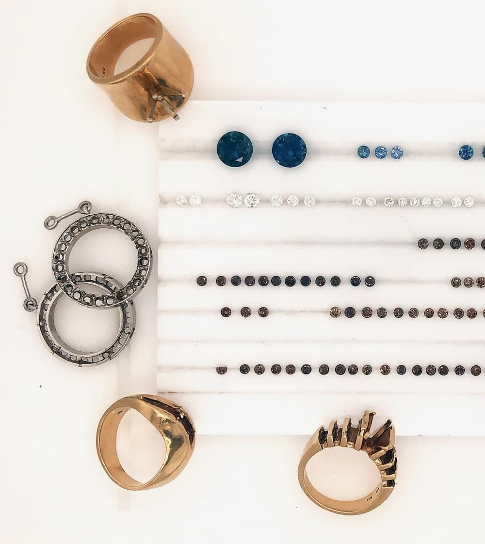 Several custom rings with empty settings beside lines of various gemstones.