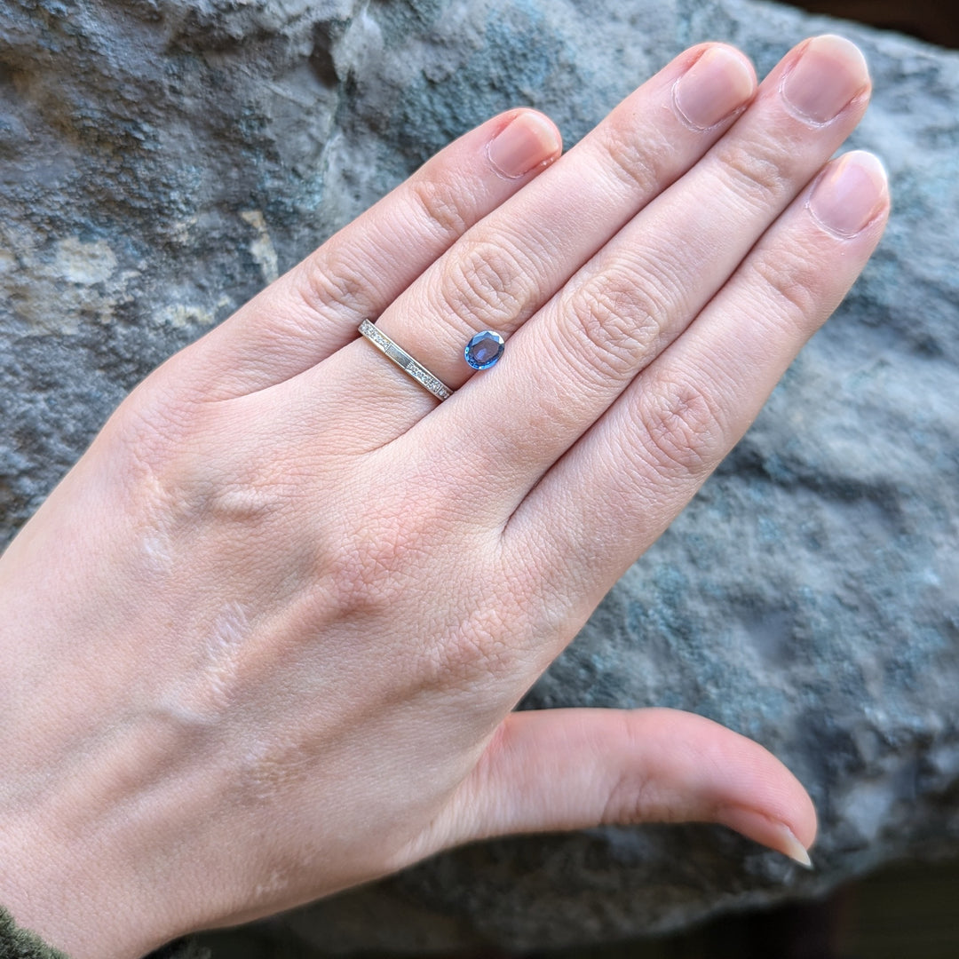 Loose oval blue Yogo sapphire gemstone on a person's hand